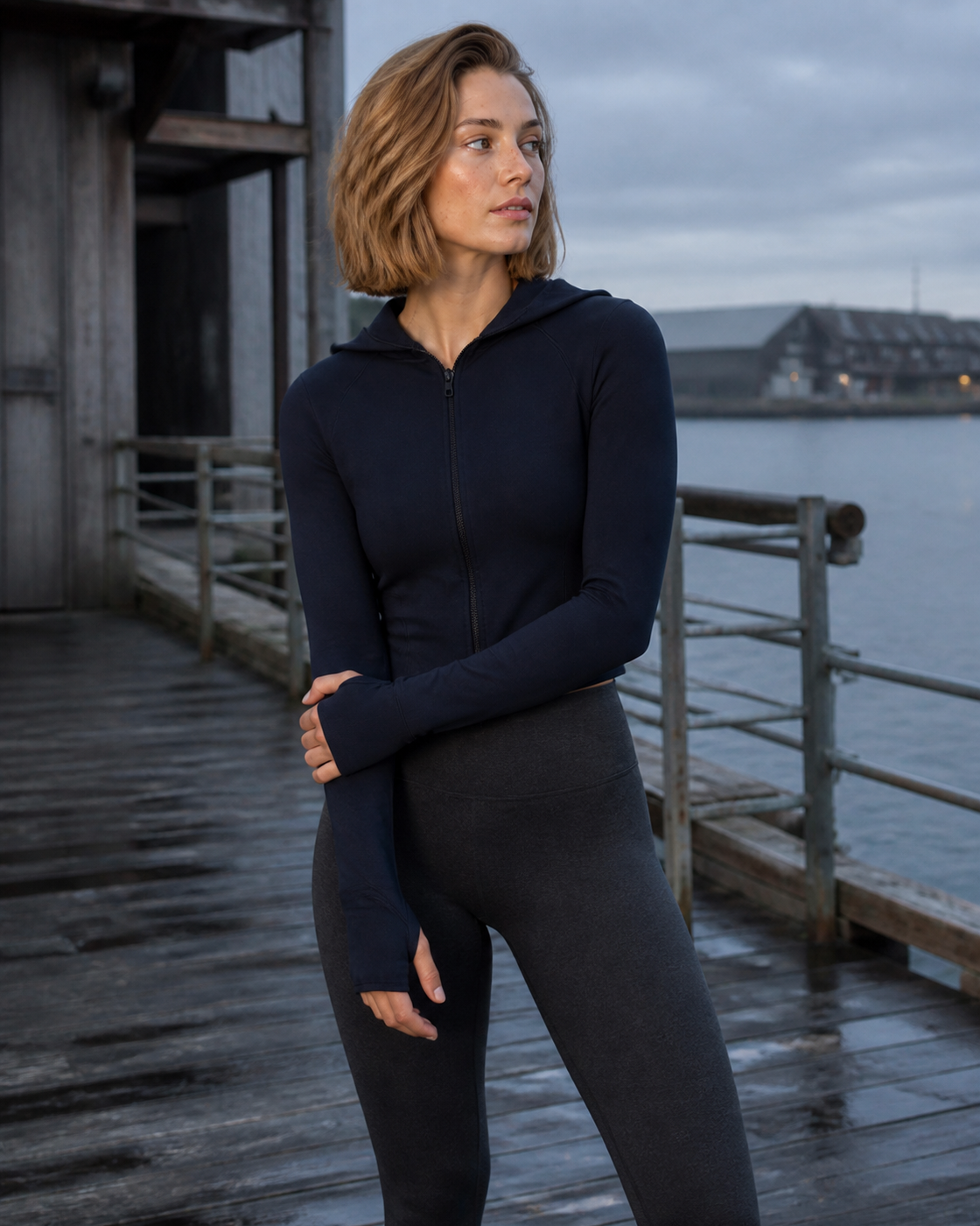 Model wearing a deep Navy hooded contour jacket at a working waterfront.