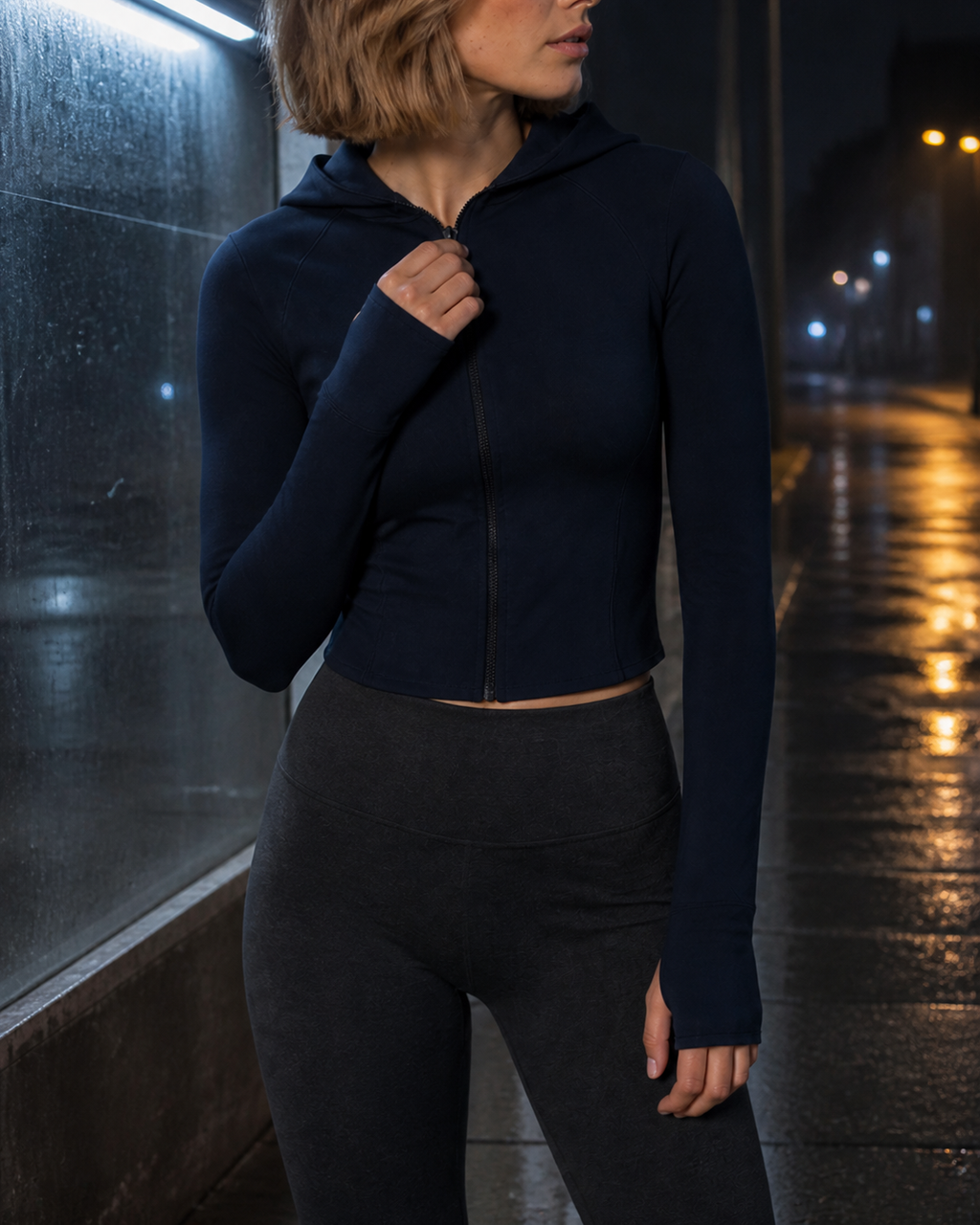 Night close-up of the deep Navy jacket zipper, hood edge and cropped hem.
