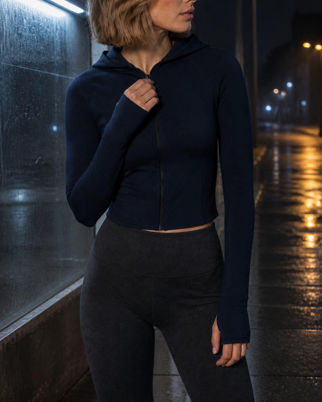Night close-up of the deep Navy jacket zipper, hood edge and cropped hem.