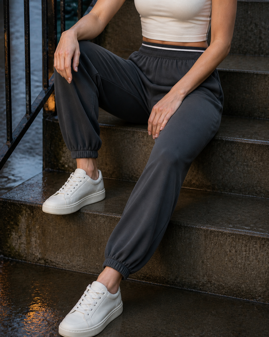 Close seated view of the striped waistband and gathered cuffs on deep Grey joggers.