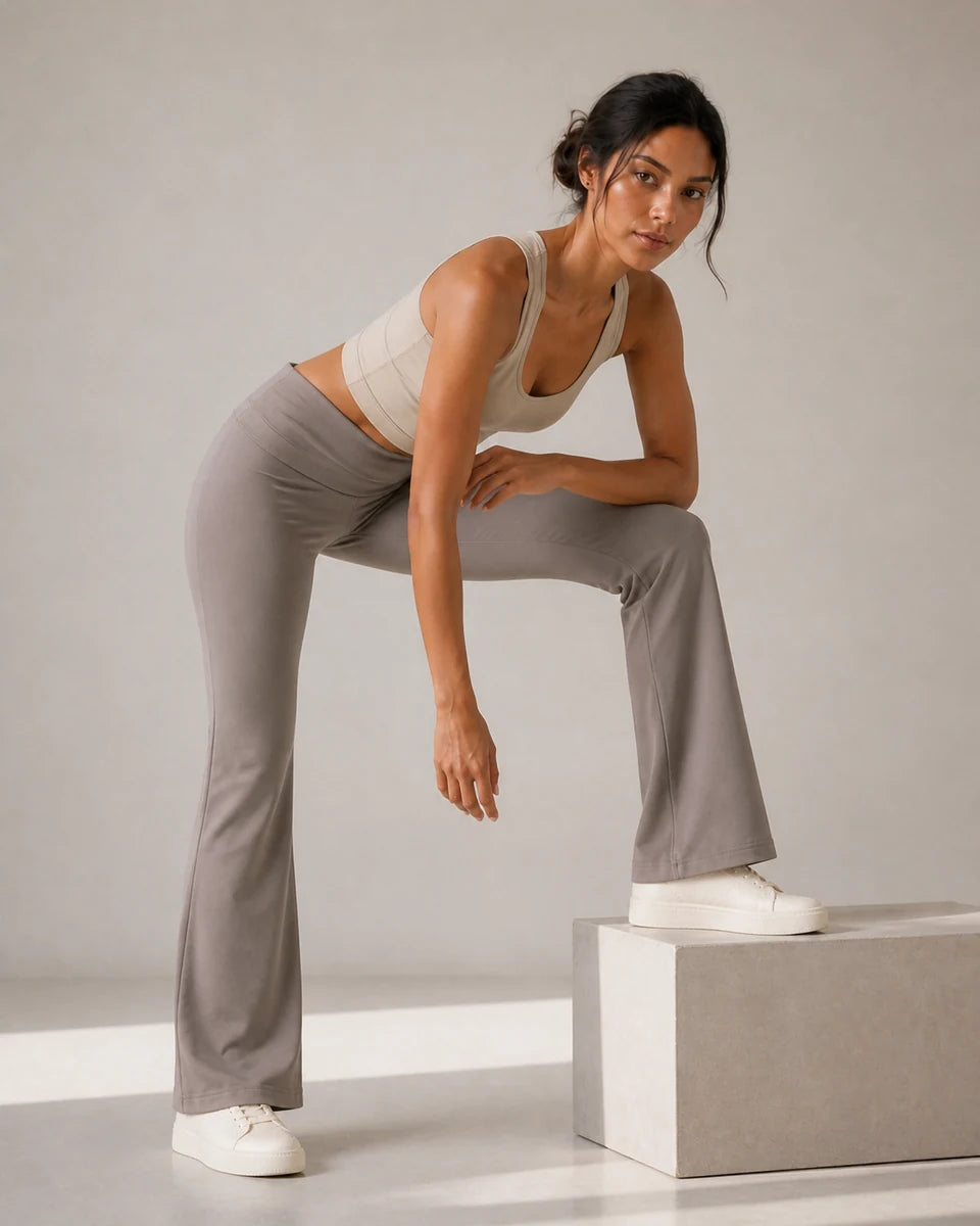 Model wearing Soft Grey Taupe Foldover Flare Pilates Pants in a low-step forward fold