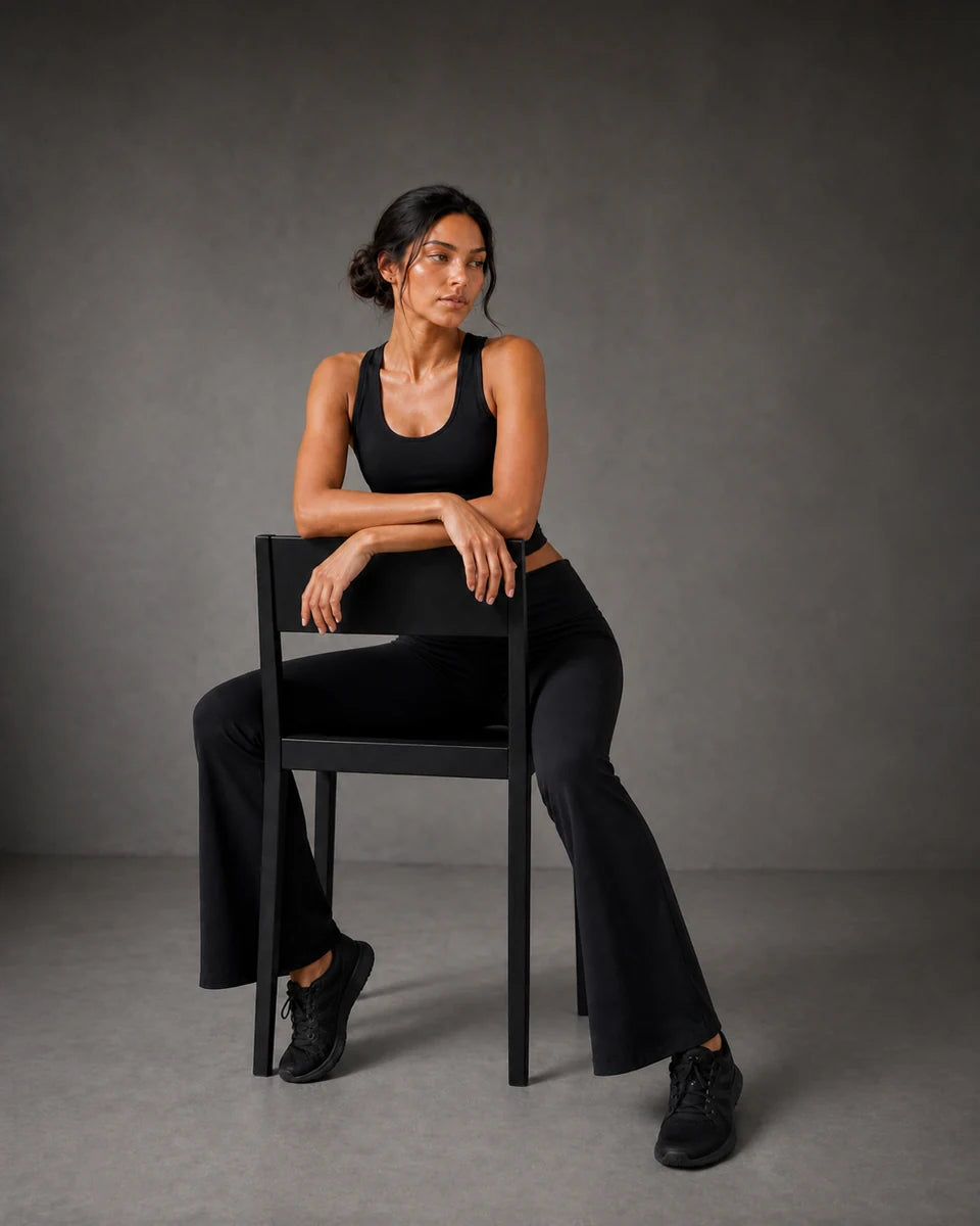 Model seated in reverse on a chair wearing Black Foldover Flare Pilates Pants
