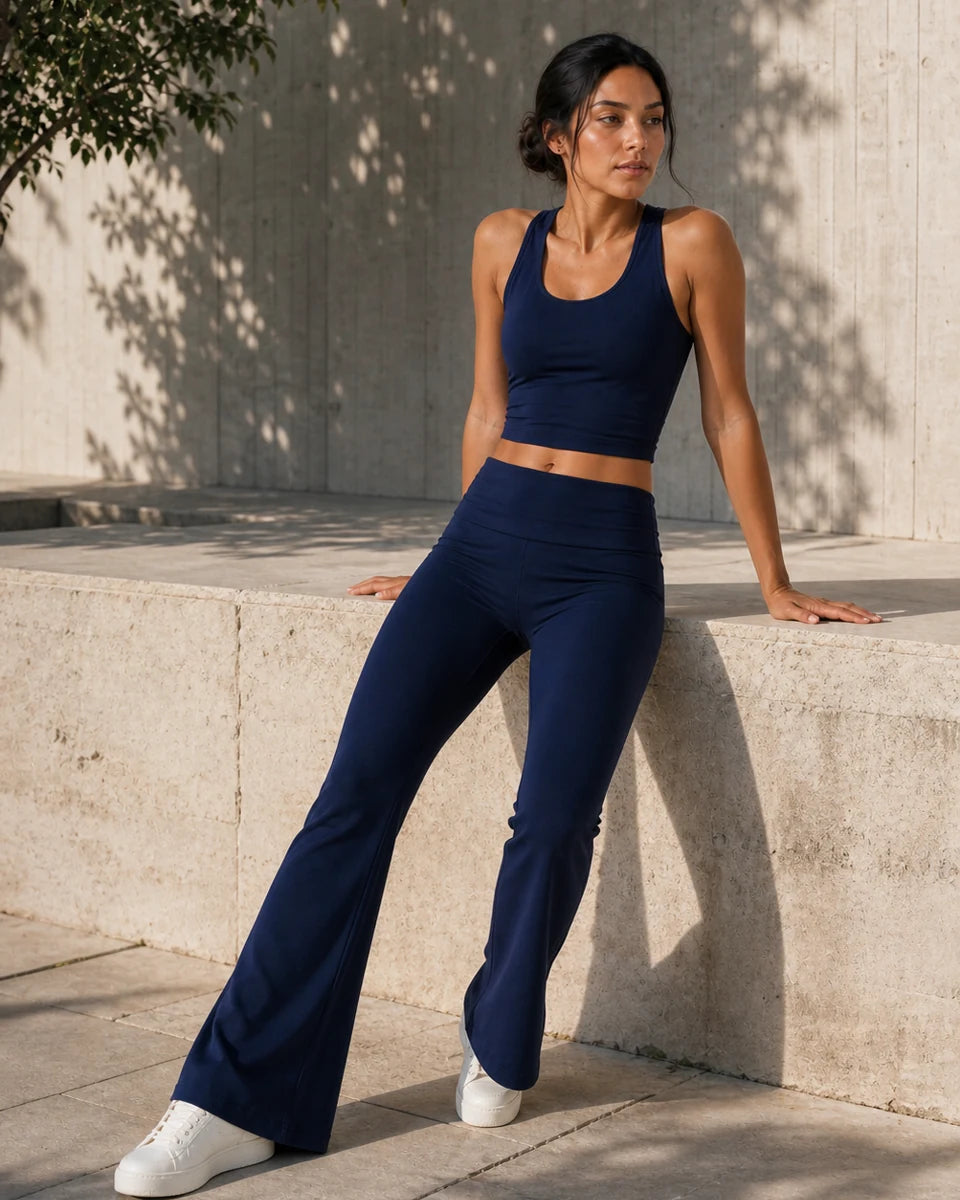 Model wearing Deep Navy Foldover Flare Pilates Pants beside a limestone wall outdoors