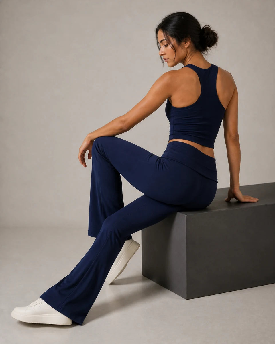 Model wearing Deep Navy Foldover Flare Pilates Pants in a seated rear three-quarter view