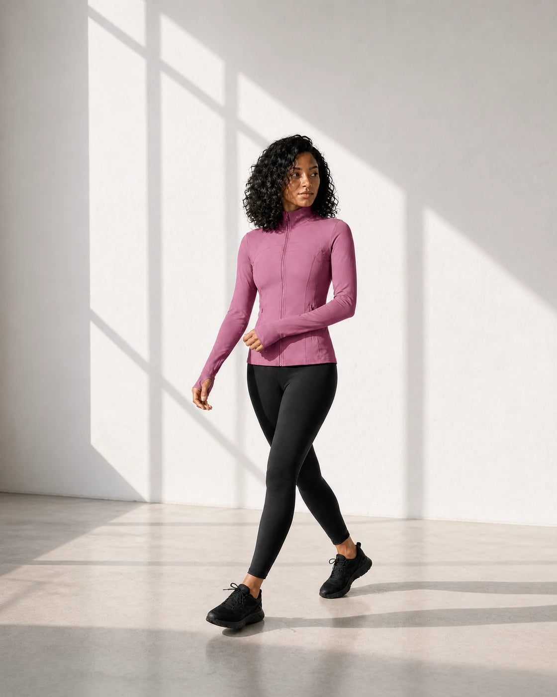 Curly-haired model walking through a sunlit studio in the Mauve Panelled Zip Training Jacket
