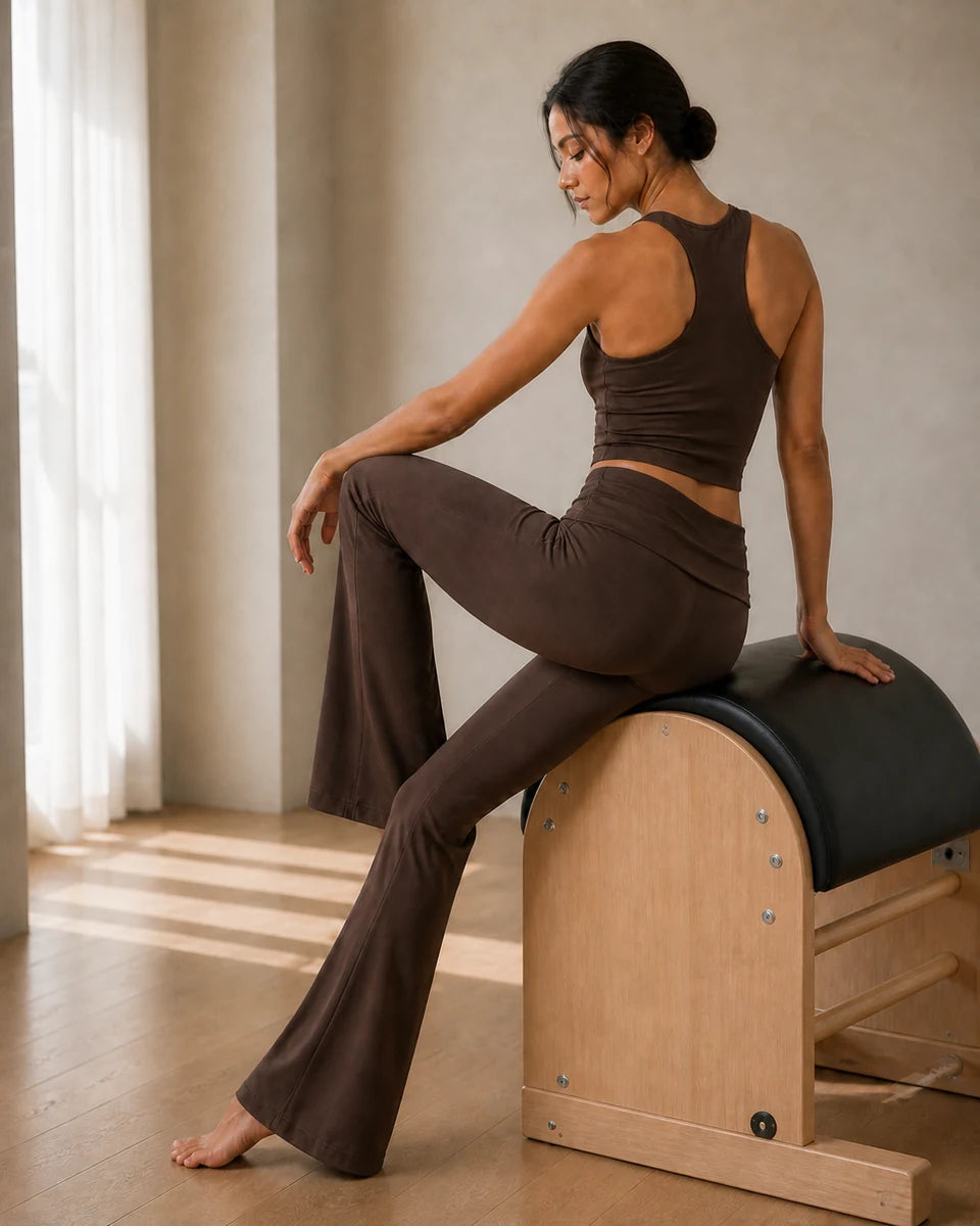 Model pausing on a Pilates ladder barrel in Mocha Brown Foldover Flare Pilates Pants