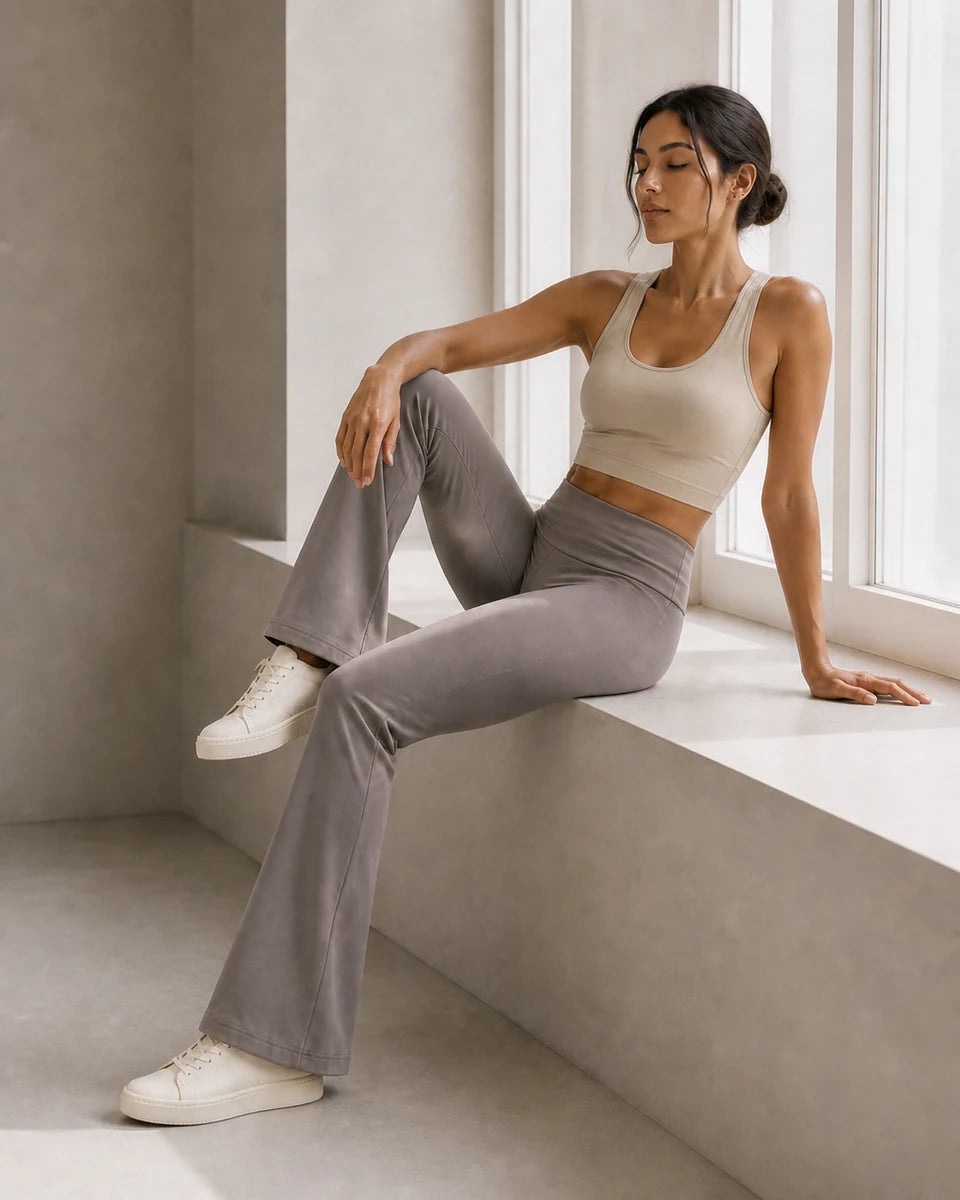 Model resting on a window bench wearing Soft Grey Taupe Foldover Flare Pilates Pants
